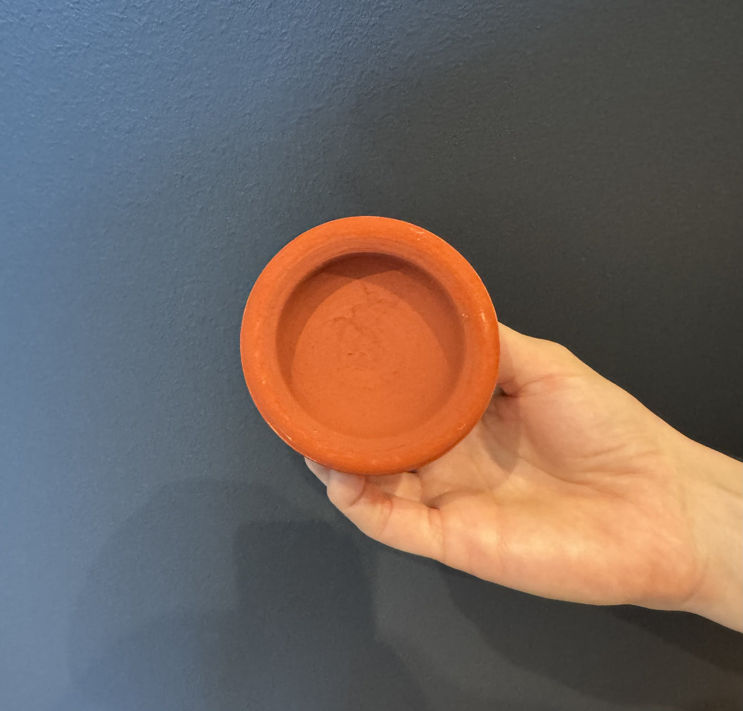 Petit tagine en terre cuite rouge traditionnel du Maroc, contenant la poudre Aker Fassi à base de coquelicot et grenade – parfait pour le maquillage naturel.