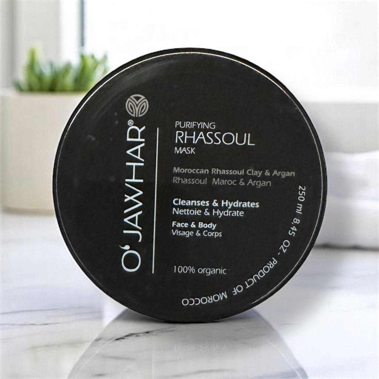 Masque Rhassoul & Argan O'Jawhar. - 100% Naturel, Visage & Corps, pot noir élégant posé dans une salle de bain moderne.