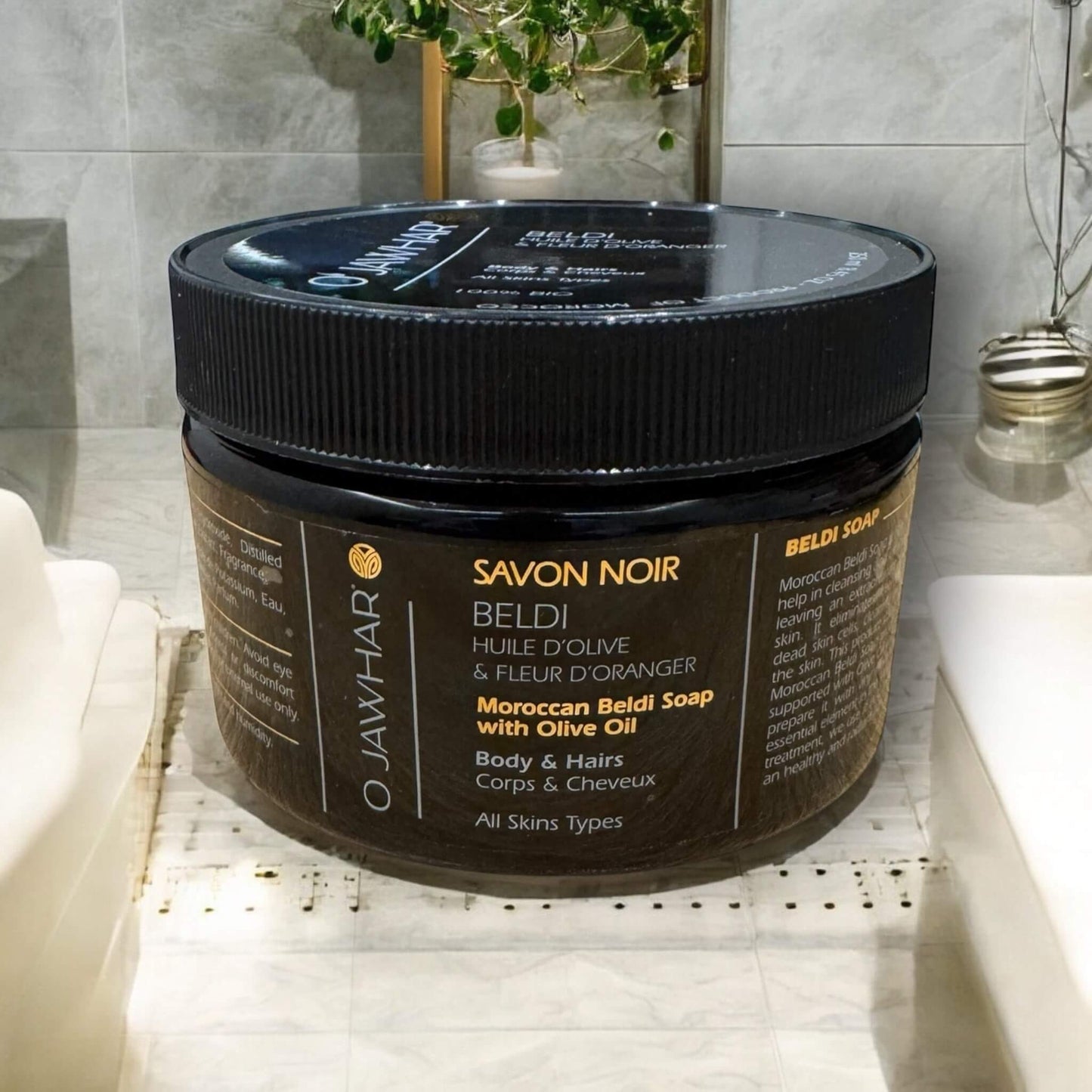 Savon noir beldi OJawhar tenu dans la main, illustrant l’utilisation réelle du produit, avec une touche humaine pour rassurer le client.
