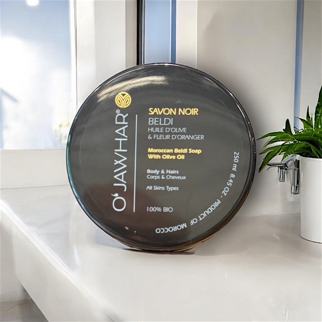 Savon noir beldi OJawhar posé dans une salle de bain claire et naturelle, évoquant détente, rituel hammam et bien-être marocain.