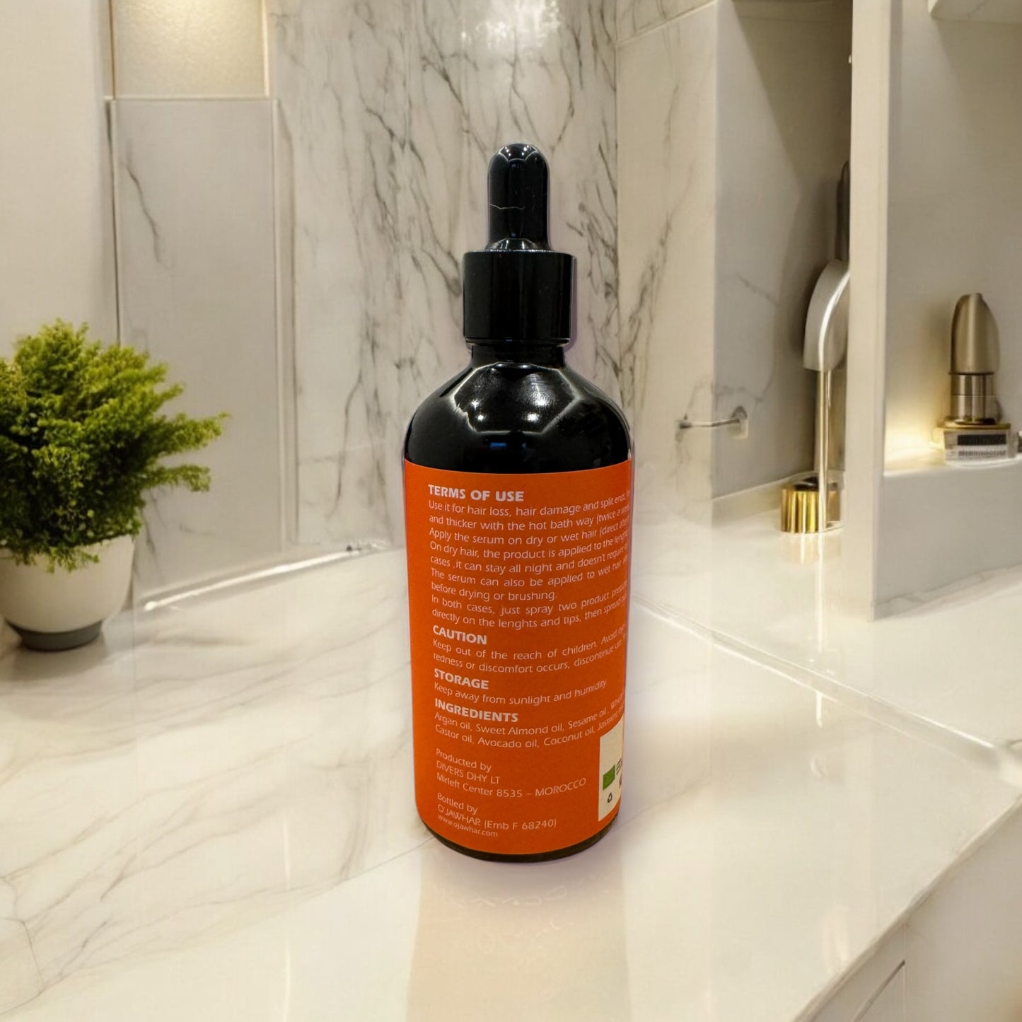 Vue dos du sérum O’Jawhar – étiquette ingrédients et conseils d’utilisation visibles, posé sur surface marbrée avec plante en arrière-plan, ambiance naturelle.