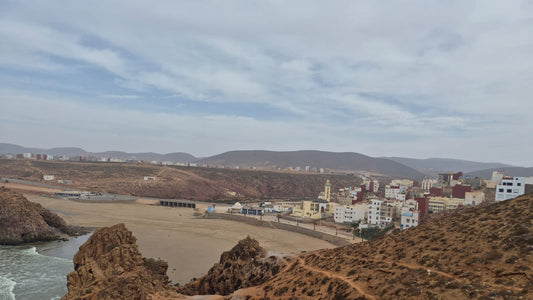 Vue panoramique de Mirleft au Maroc, entre plage, falaises et habitations, illustrant l’origine locale des produits naturels O’Jawhar.