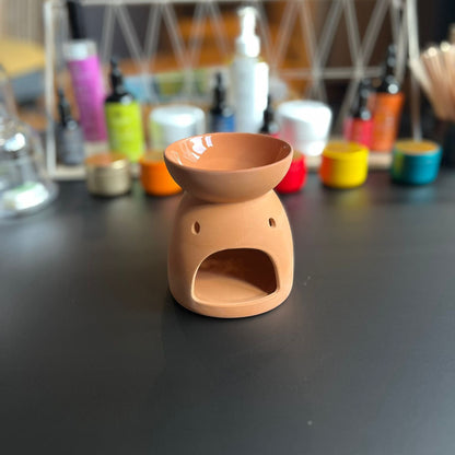 Brûleur à fondant en céramique effet terre cuite vu de dos, lumière douce et ambiance apaisante.