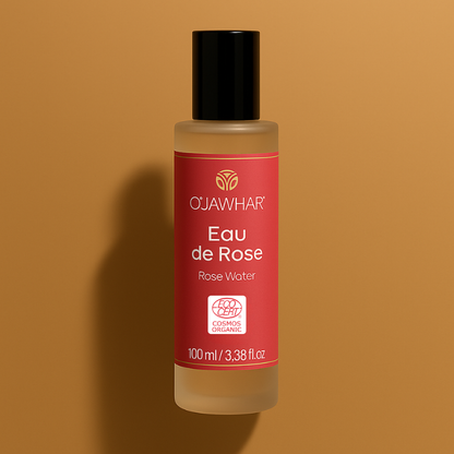 Flacon d’Eau de Rose O’Jawhar 100 % BIO certifiée Ecocert, posé sur fond ocre avec lumière douce.