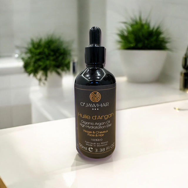 Flacon d’huile d’argan O’Jawhar dans une salle de bain – rituel beauté marocain.