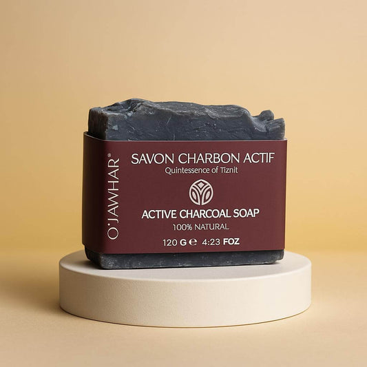 Savon Charbon Actif O’Jawhar posé dans un podium élégante — savon naturel purifiant au charbon inspiré de Tiznit, 100 % naturel.
